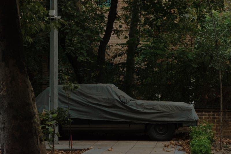 A car under a fitted outdoor cover in winter - a stand-in for the Budge Lite Car Cover, not a photograph of this model
